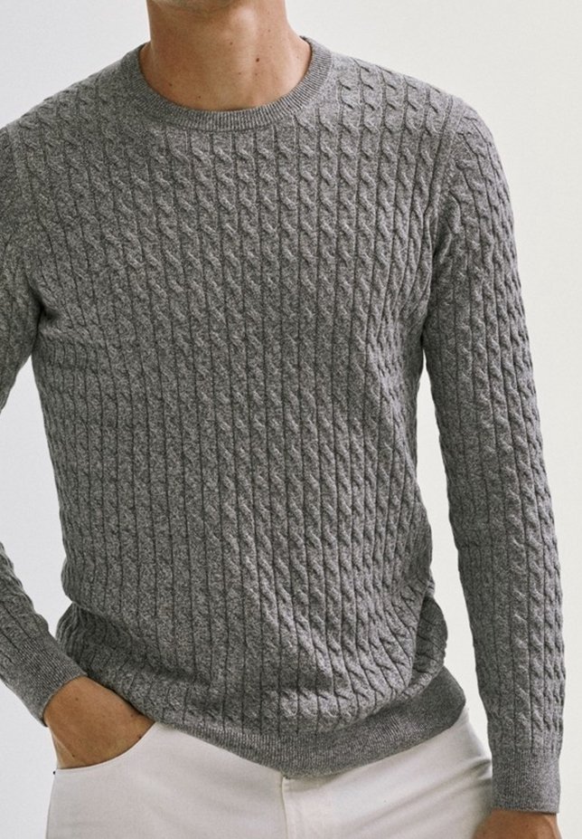 Pull gris en maille avec un motif torsadé texturé, col rond et manches longues. Le tissu semble doux et légèrement extensible.