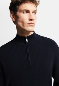 Navy Quarter-Zip-Pullover aus strukturiertem Rippstoff. Verfügt über einen Stehkragen und einen silbernen Reißverschluss. Keine sichtbaren Muster oder Akzente.