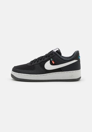 Czarny niski sneaker z białym logo Nike, teksturowaną podeszwą i widoczną wewnątrz kołnierza podszewką z polaru, pokazany z boku na jednolitym tle.