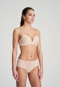 Vaalea beige rintaliivi- ja korkeavyötäröisten alushousujen setti. Rintaliiveissä on sileä kangas, pehmustetut kupit ja koristeelliset pyöreät hihnat; alushousuissa on minimalistinen muotoilu.