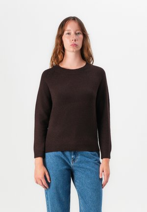 Dark brown knitted sweater with a round neckline and raglan sleeves, paired with light blue jeans. Soft texture, simple design.