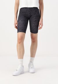 Shorts de vélo en tissu extensible avec un imprimé léopard noir, longueur mi-cuisse, dotés d'une taille élastique et d'une texture lisse.