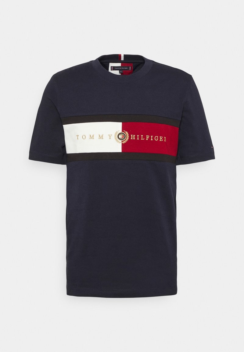 Mörkblå bomullströja med korta ärmar och rund halsringning, med en horisontell design i rött, vitt och svart med "TOMMY HILFIGER"-logotyp.