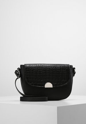Sort crossbody-taske med flap i krokodilleskinstruktur, sølvspænde og justerbar rem vist på hvid piedestal.