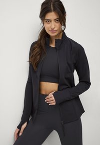 Zwarte sportjack met hoge kraag, volledige rits en aangesloten silhoët. Heeft lange mouwen en een naadloos ontwerp dat aansluit bij bijpassende kleding.