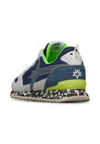 Zapatilla deportiva de ante en azul marino y gris con detalles en verde lima, suela texturizada y un patrón de camuflaje distintivo en la media suela.