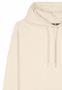 Felpa beige con cappuccio e lacci, con un'etichetta parziale visibile all'interno della zona del collo.