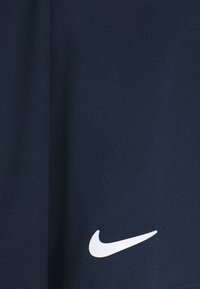 Sot shorts urheilu navy sinisestä kevyestä kankaasta, jossa on näkyvä valkoinen Nike-logo vasemmassa alakulmassa.
