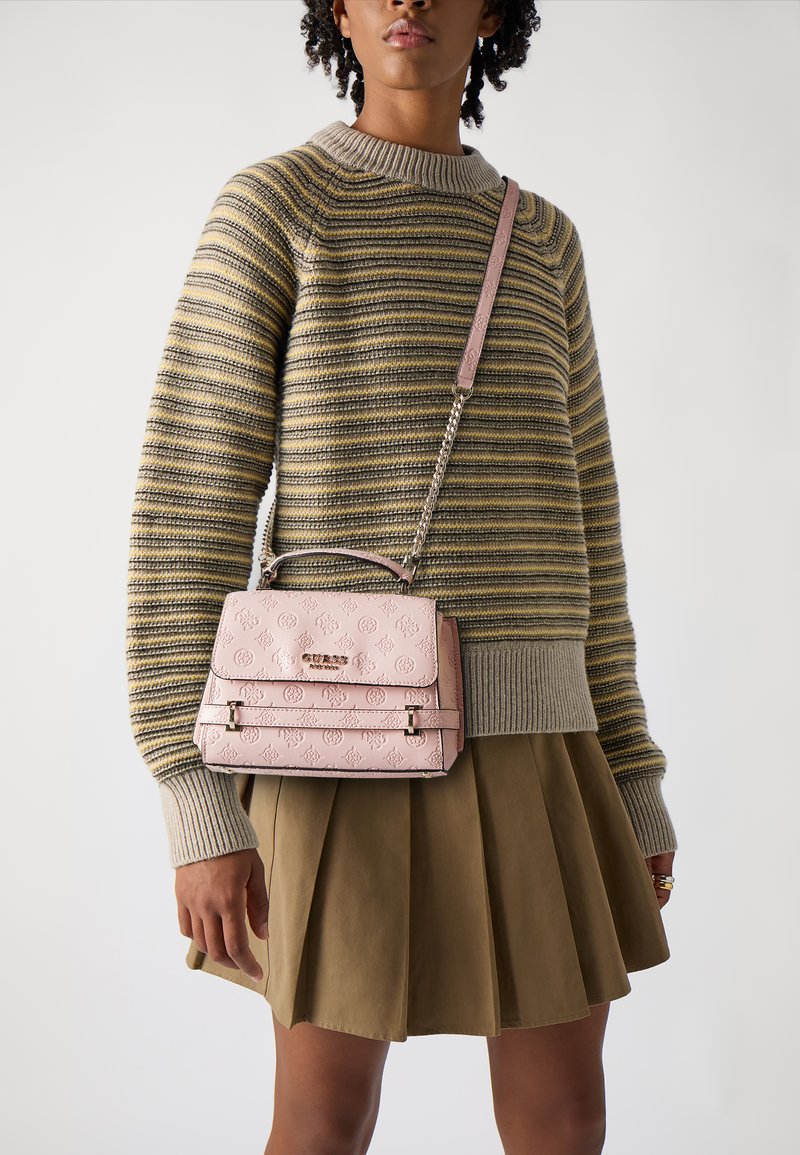 Borsa rosa realizzata in materiale texturizzato, con manico superiore, tracolla a catena e design con logo impresso, indossata sopra un maglione a righe e una gonna.