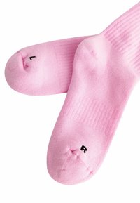 Calzini in cotone rosa chiaro con texture a coste; contrassegnati con 'L' e 'R' sulle punte per l'orientamento sinistro e destro.