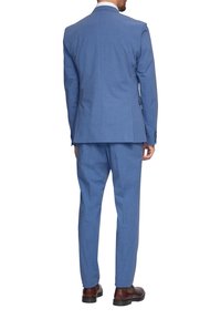 Dopasowany niebieski garnitur z teksturowanej tkaniny, z marynarką z jednym rozcięciem i spodniami z gładkim przodem. Brązowe buty wizytowe dopełniają całość.