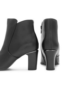 Čierne kožené členkové topánky s guľatou špičkou, bočným zipsom a masívnym podpätkom, ktorý má textúrovaný povrch a lesklý akcent na základni.