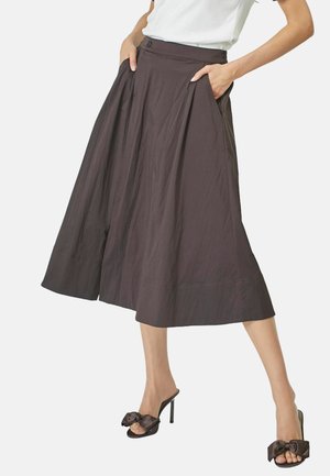 Brown, wide-legged skirt with pleats, mid-calf length, side pockets, paired with black mules featuring a bow accent.