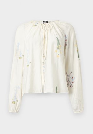 Blouse crème à manches longues avec boutons sur le devant, encolure à cordon et broderie florale multicolore sur les manches et le devant.