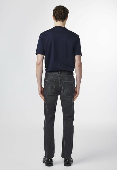 Navy short-sleeve t-shirt paired with dark gray jeans. The jeans feature standard back pockets and a straight-leg cut. Flat black shoes complete the look.