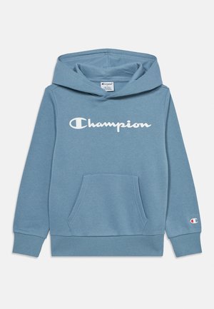 Jasnoniebieska bluza Champion z kapturem, z przednią kieszenią i białym logo Champion na piersi oraz małym logo na mankiecie lewego rękawa.