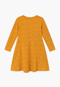 Pitkähihainen mekko kirkkaan keltaisena, jossa on valkoisia kukkakuvioita, liehuva helma, pyöreä pääntie ja pehmeä, teksturoidusta kankaasta valmistettu.