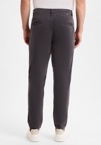Gray cotton trousers with a textured finish, featuring two back pockets and elasticized cuffs. Paired with light-colored sneakers.