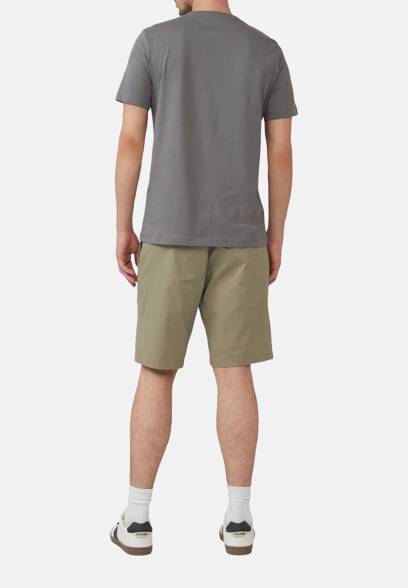 Grijze katoenen t-shirt, achteraanzicht, gecombineerd met lichtgroene shorts, simpele ontwerp, en witte crew-sokken met schoenen met zwarte accenten.