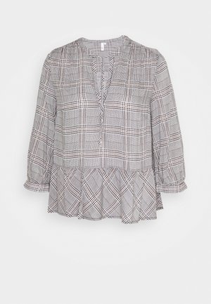 Blouse à manches longues à carreaux gris et blanc avec fente en V au col et ourlet à volants, tissu léger et coupe ample.