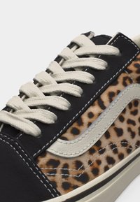 Μαύρο και λεοπάρ αθλητικό παπούτσι με λευκή ραφή, λευκά κορδόνια και λευκή δερμάτινη λεπτομέρεια κυματισμού στο πλάι.
