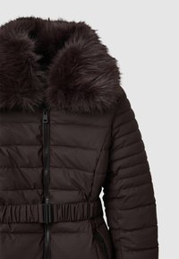 Giacca puffer marrone con colletto in pelliccia artificiale, chiusura con zip e vita cinchata. Tessuto strutturato con trapuntatura orizzontale e due tasche laterali.