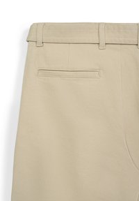 Pantaloni in cotone beige con frontale piatto, passanti per cintura e una singola tasca posteriore con bordo cucito. Tessuto liscio e design sartoriale.