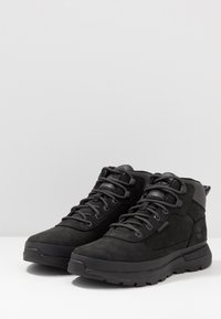Bottines noires en suède, avec des surfaces texturées, un bout rond, des lacets robustes et une semelle en caoutchouc avec des motifs de traction.