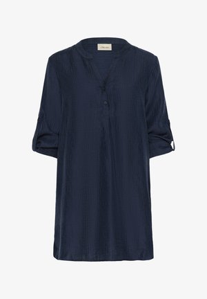 Tumši zils, īsām piedurknēm tunika ar mandarina tipa apkakli, pogu aizdari un teksturētu audumu. Iezīmētas sarullētas piedurknes ar poga lentām.