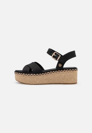 Sort platform sandal med krydsede stropper af stof, justerbar ankelspænde og flettet jutesål.