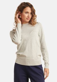 Light gray long-sleeve sweater in soft fabric, round neckline, ribbed cuffs, and hem. Features a subtle logo detail at the side.