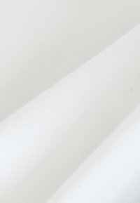 Tessuto bianco con strisce diagonali strutturate, con variazioni sottili di tonalità e una finitura morbida e liscia su sezioni sovrapposte.