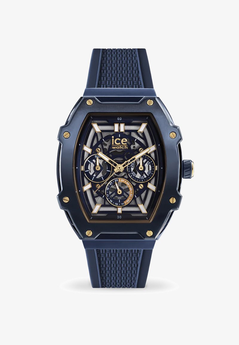 Tamsiai mėlynas silikono laikrodis su šešiakampiu korpusu, auksinėmis detalėmis ir tekstūruotu dirželiu; turi daugiadialį chronografą ir permatomą ciferblatą.