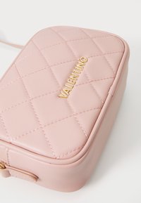 Bolsa de pele rosa matelassada com o logótipo dourado "Valentino", em forma retangular, textura suave e detalhe de costura em contraste.