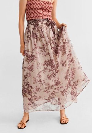 Jupe longue en tissu léger beige transparent avec un motif floral dans des tons de rose et de marron. Taille nouée et silhouette fluide.