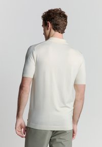 Lichtcrème poloshirt met korte mouwen, met een zachte textuur en een klassieke kraag, voorzien van ribgebreide manchetten en een rechte zoom.