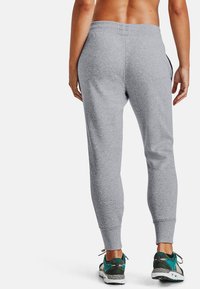 Grå bomullsjoggers med slim fit, med ribbade muddar och elastisk midja. Ett par gröna och svarta sportskor synliga.