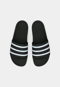 Sandales à glissière noires avec trois bandes blanches. Semelle intérieure texturée pour une meilleure adhérence, matériau supérieur doux et logo gravé sur la surface supérieure.