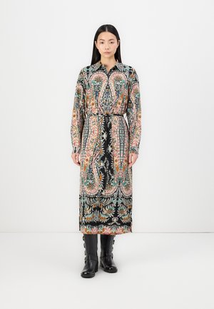 Svart, mønstret lang skjortekjole med flerfargede paisleymotiver, knapper på fronten, belte i midjen og lange ermer, iført med svarte knelang støvler.