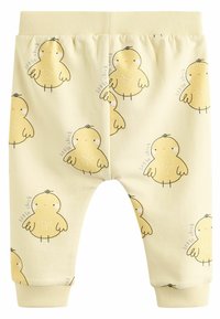 Dzelteni kokvilnas bikses ar atkārtotu vistu rakstu. Elastīga josta un piedurknes, gluda tekstūra. Akcenti ietver mazu tekstu "mazā vista".