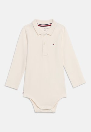 Body bébé écru à manches longues avec col, deux boutons sur le devant, fermeture pressionnée en bas et petit logo brodé sur la poitrine.