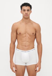 Witte boxershorts met een rekbare tailleband met een logo. De stof lijkt glad, aansluitend en heeft een minimalistisch ontwerp.