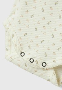 Ribbade bomull bodysuit i krämfärg med pastellfärgad blommönster. Har tryckknappar med svarta kanter och vågiga kanter.