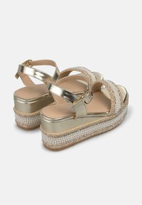 Gouden platform sandalen met textuur, gevlochten jute details en versierde banden. Gesp sluiting, gevoerd voetbed en stijlvolle uitstraling.