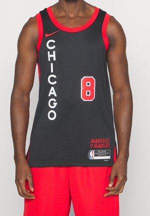 Mand iført sort og rød Chicago basketballtrøje med nummer 8 og røde shorts, stående mod en ensfarvet baggrund.