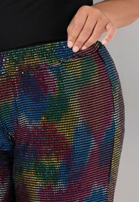 Leggings con diseño de strass que presentan un fondo negro y una silueta ajustada, adornados con motivos multicolores y embellishments similares a diamantes.