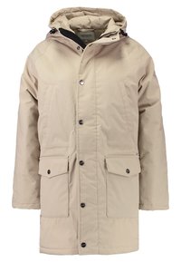 Chaqueta aislante beige con capucha, botones de presión, dos bolsillos frontales y un suave forro interior. Hecha de material resistente a las inclemencias del tiempo.