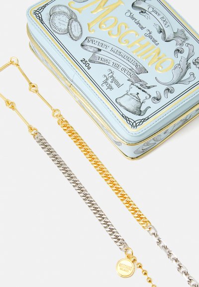 Cutie de la Moschino, de culoare bleu deschis, împodobită cu litere aurii. Două curele din lanț: una aurie, una argintie, având un mic etichetă de marcă pe lanțul argintiu.