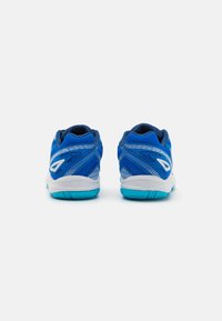 Baskets de sport bleu avec une tige en mesh texturé, des détails blancs et une semelle turquoise. Elles disposent d'un talon rembourré et d'un design épuré.