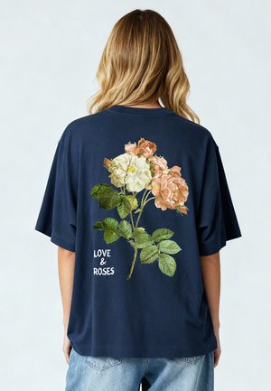 Marineblaue Baumwoll-T-Shirt mit lockerer Passform. Mit floralem Design aus weißen und Pfirsichrosen, mit dem Text "LIEBE & ROSEN" am unteren Ende.